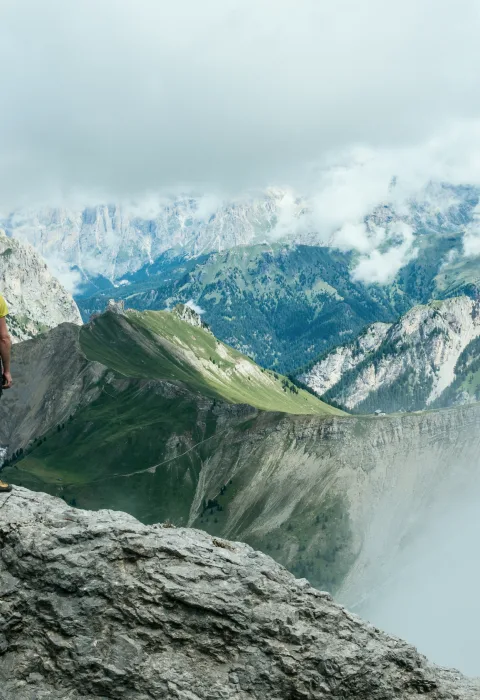 Blick von einem Felsvorsprung über ein wolkenverhangenes Bergmassiv